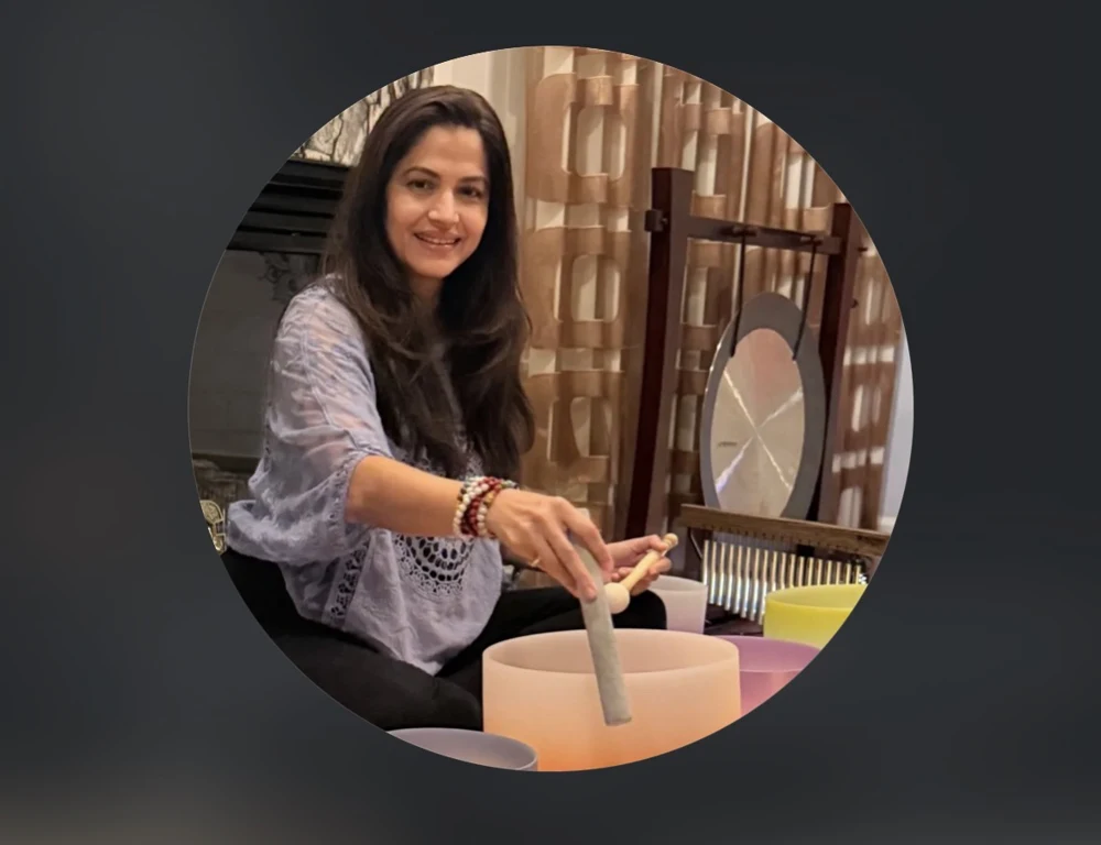 Dr. Devangi Pathak smiling while playing a singing bowl